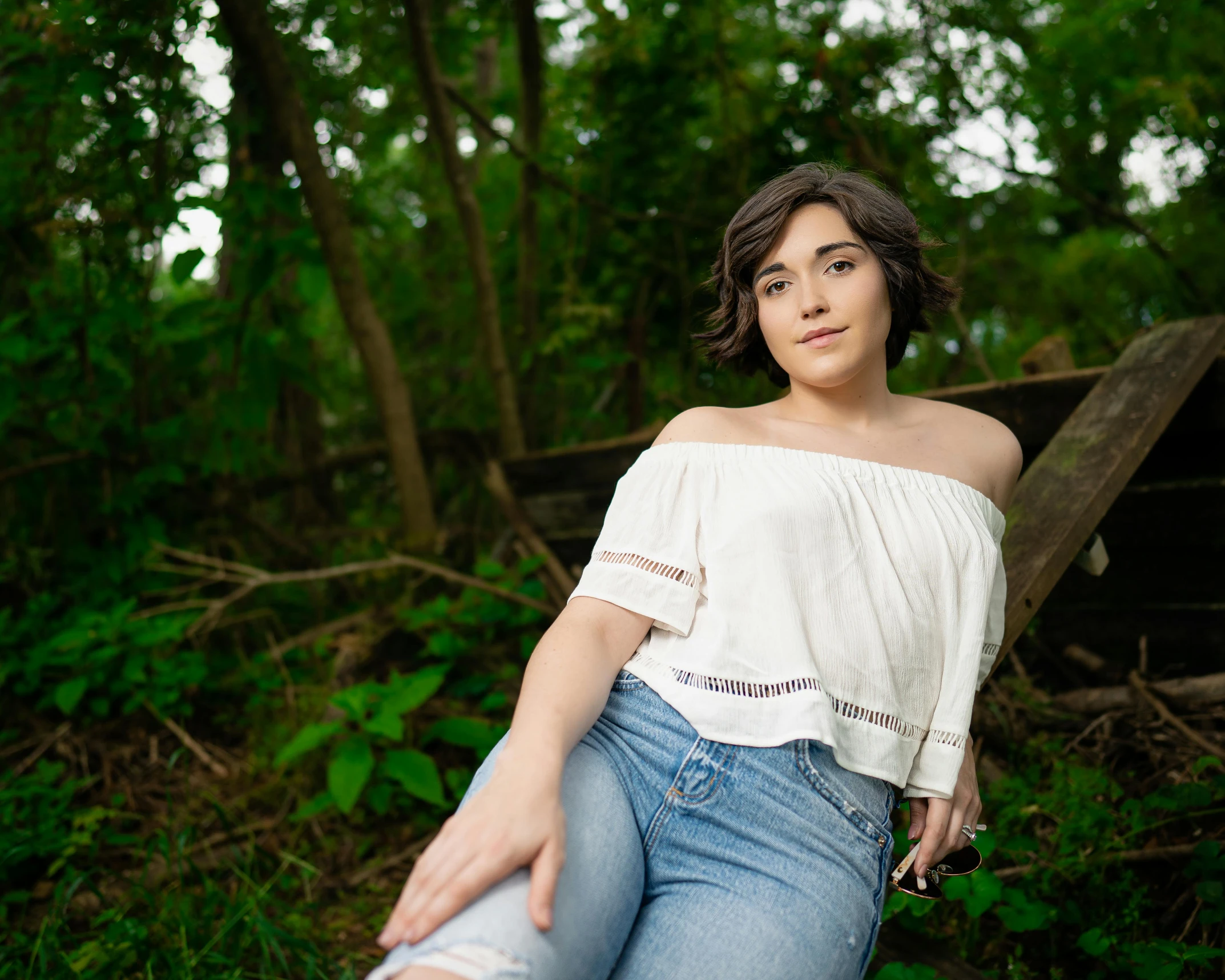 a woman sitting on a log in the woods, an album cover, by Everett Warner, unsplash, renaissance, off the shoulder shirt, rebecca sugar, white shirt and jeans, she is about 1 6 years old