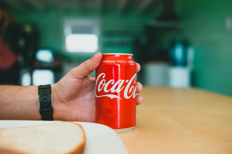 a person holding a can of coca cola on a table, pexels contest winner, 🦩🪐🐞👩🏻🦳, rectangle, cooked, super high resolution