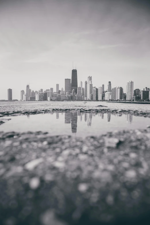 a black and white photo of a city skyline, by Robbie Trevino, unsplash contest winner, visual art, standing in shallow water, from wheaton illinois, standing on rocky ground, low point of view