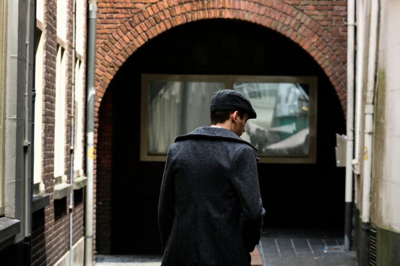 a man walking down a narrow alley way, inspired by Louis Stettner, unsplash, an oversized beret, utrecht, in front of a garage, sherlock holmes