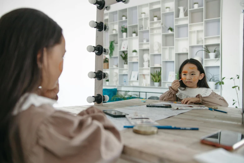 a woman sitting at a table in front of a mirror