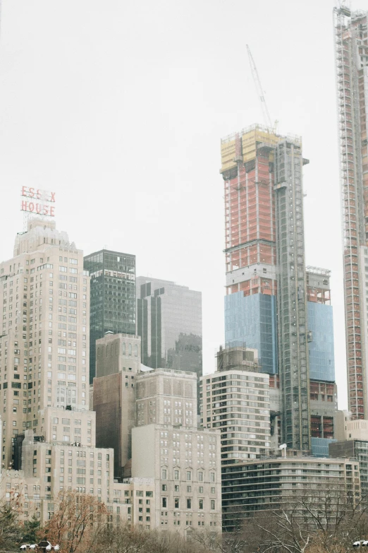 a man riding a skateboard down a street next to tall buildings, by William Berra, trending on unsplash, modernism, construction site, manhatten on top of skyscrapers, 2000s photo, building facing