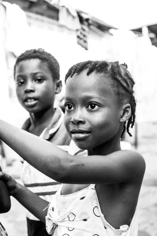 a group of young children standing next to each other, a black and white photo, by Chinwe Chukwuogo-Roy, pexels contest winner, looking across the shoulder, two still figures facing camera, brightly lit, a hand