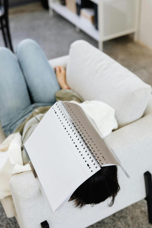a woman laying on a couch reading a book, an album cover, trending on pexels, perforated metal, white mechanical details, product introduction photo, holding a clipboard