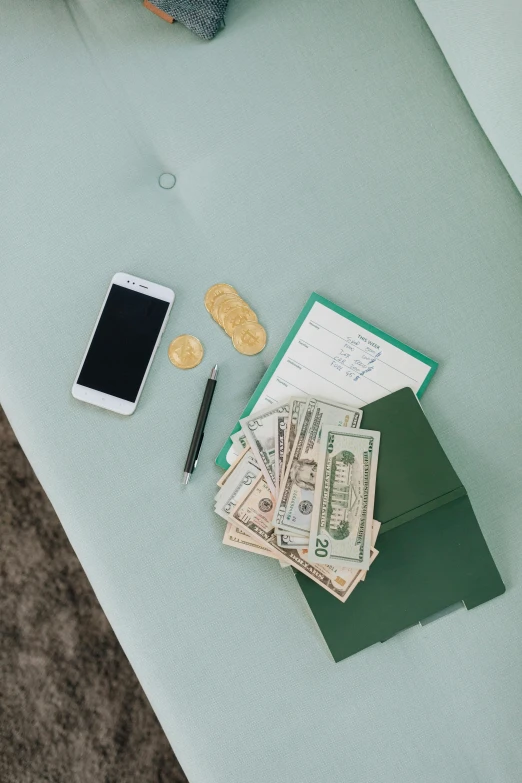 a pile of money sitting on top of a table next to a cell phone, miscellaneous objects, seafoam green, multiple stories, product shot