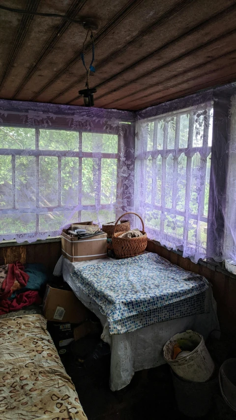 a bed sitting inside of a bedroom next to a window, an album cover, by Abram Arkhipov, cottagecore hippie, ((purple)), makeshift house, photographed for reuters