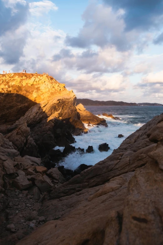 a man standing on top of a rock next to the ocean, les nabis, sunset panorama, ochre, sparkling cove, slide show