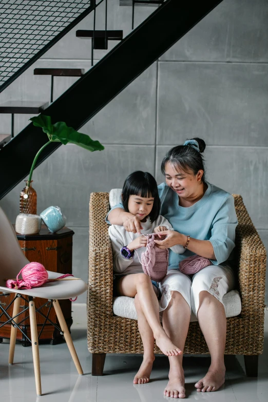 a woman sitting on top of a chair next to a little girl, inspired by Ni Yuanlu, pexels contest winner, crochet, cozy arm chairs, singapore, sustainable materials