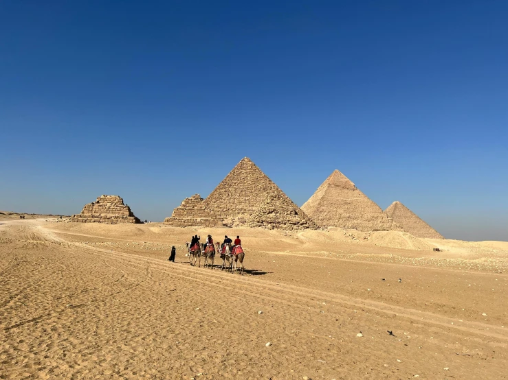 a group of people riding horses across a desert, egyptian art, pexels contest winner, pyramids of giza, avatar image, ground level shot, iphone photo