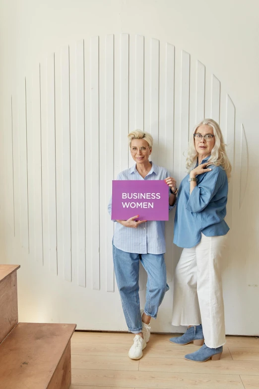 two women standing next to each other holding a sign, pexels contest winner, business logo, white haired lady, full body image, thumbnail
