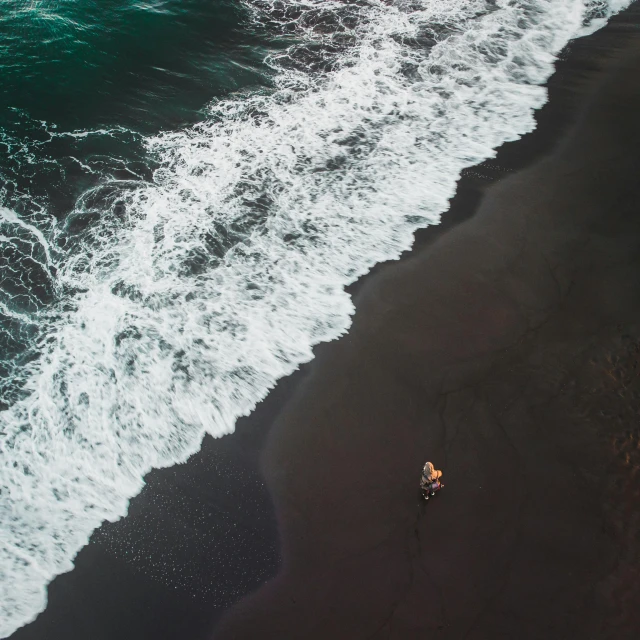 a person riding a surfboard on top of a black sand beach, by Daniel Seghers, pexels contest winner, minimalism, bird's eye, calmly conversing 8k, hunting, sitting alone