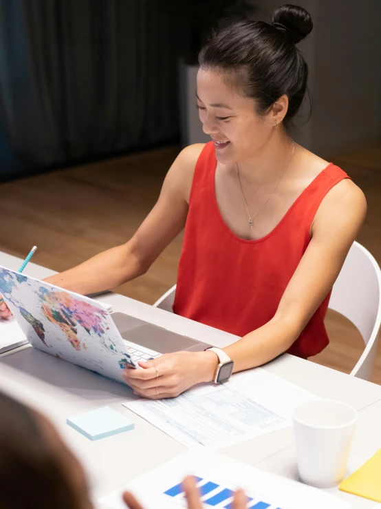 a woman sitting at a table working on a laptop, inspired by helen huang, on vellum, looking happy, professional profile photo, holding a clipboard