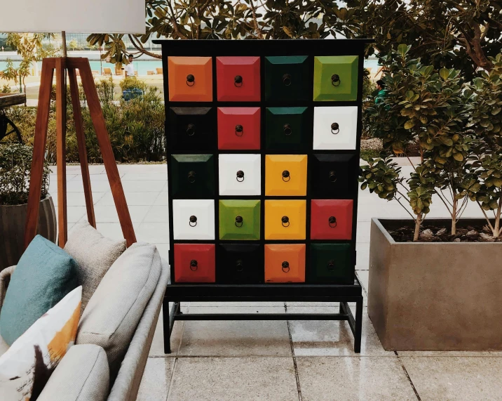 a colorful chest of drawers sitting on top of a patio, an album cover, by Emma Andijewska, unsplash, squares, black furniture, collection of louvre, 15081959 21121991 01012000 4k