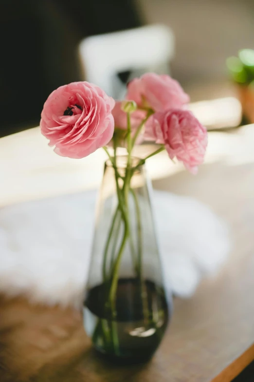 a vase filled with pink flowers sitting on a table, unsplash, angled, poppy, soft natural light, upclose