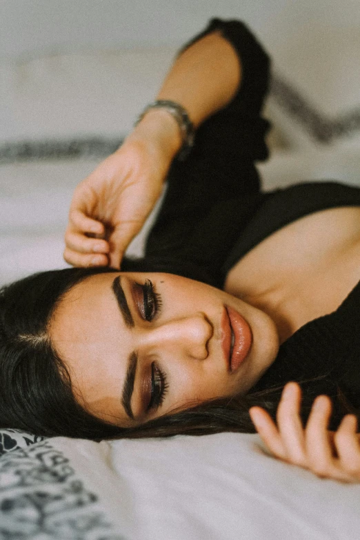 a beautiful young woman laying on top of a bed, inspired by Elsa Bleda, trending on pexels, beautiful arab woman, angular eyebrows, black, music video