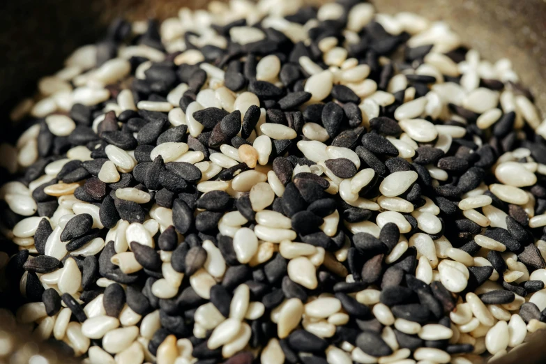 a wooden bowl filled with black and white rice, by Nina Hamnett, unsplash, mingei, moai seedling, zoomed in, seeds, various sizes