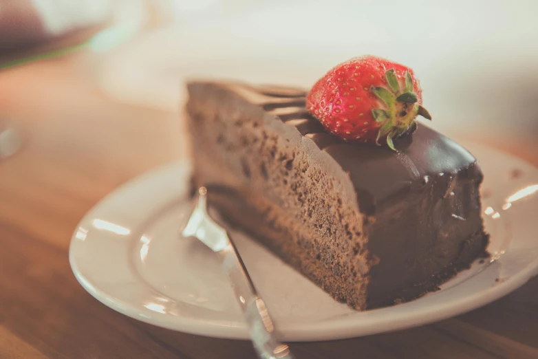 a piece of chocolate cake with a strawberry on top, pexels contest winner, romanticism, profile image, fan favorite, humongous, sitting on a mocha-colored table