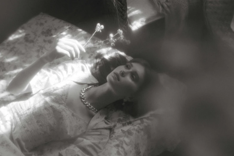 a black and white photo of a woman laying on a bed, inspired by Cecil Beaton, lady with glowing flowers dress, enveloped in ghosts, dreamy light, still from l'estate