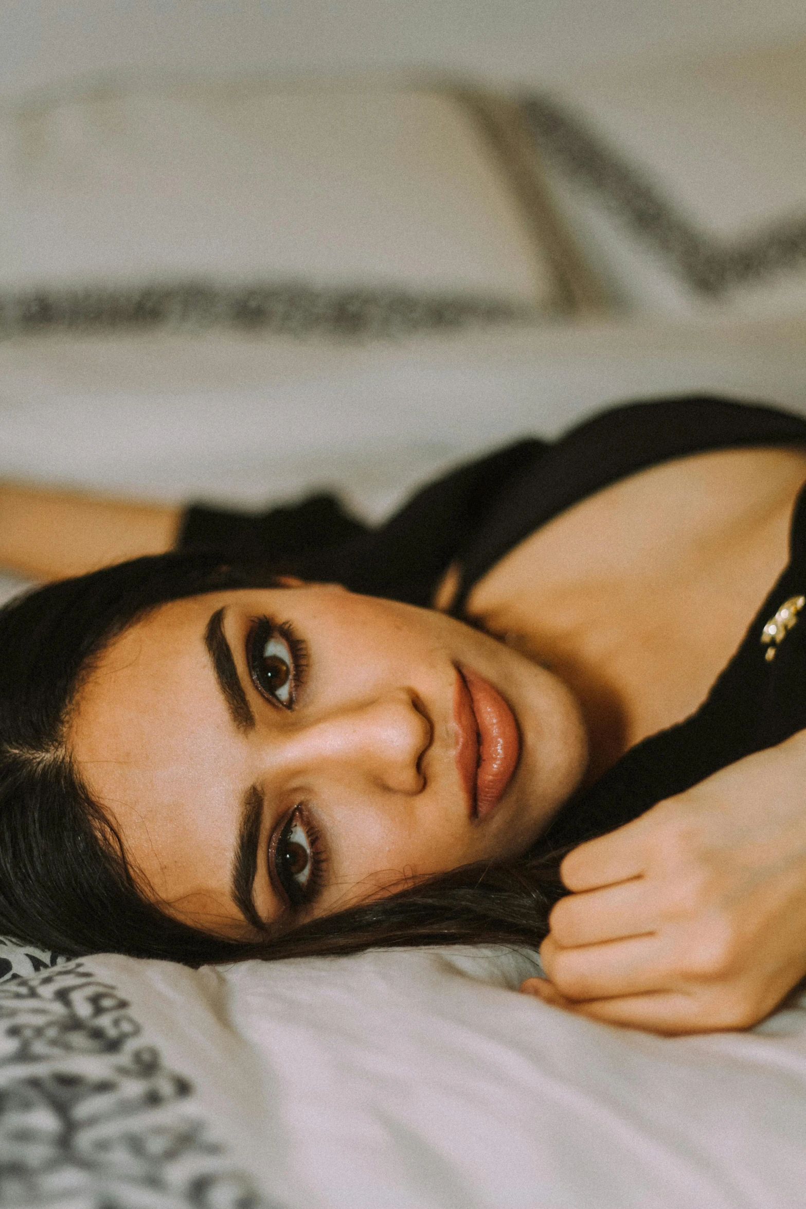 a beautiful young woman laying on top of a bed, by Julia Pishtar, trending on pexels, hurufiyya, middle eastern skin, straight eyebrows, black, low quality photo