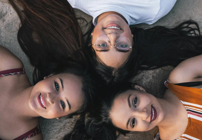 a group of young women standing next to each other, pexels contest winner, incoherents, smiling down from above, three heads, indian girl with brown skin, laying down