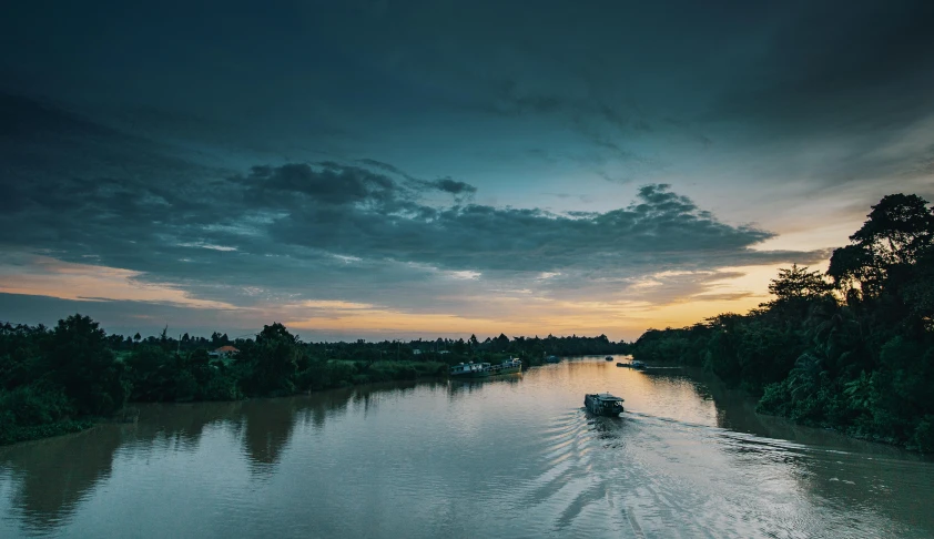 a boat traveling down a river under a cloudy sky, a picture, unsplash contest winner, hurufiyya, twilight ; wide shot, cambodia, wide high angle view, slide show