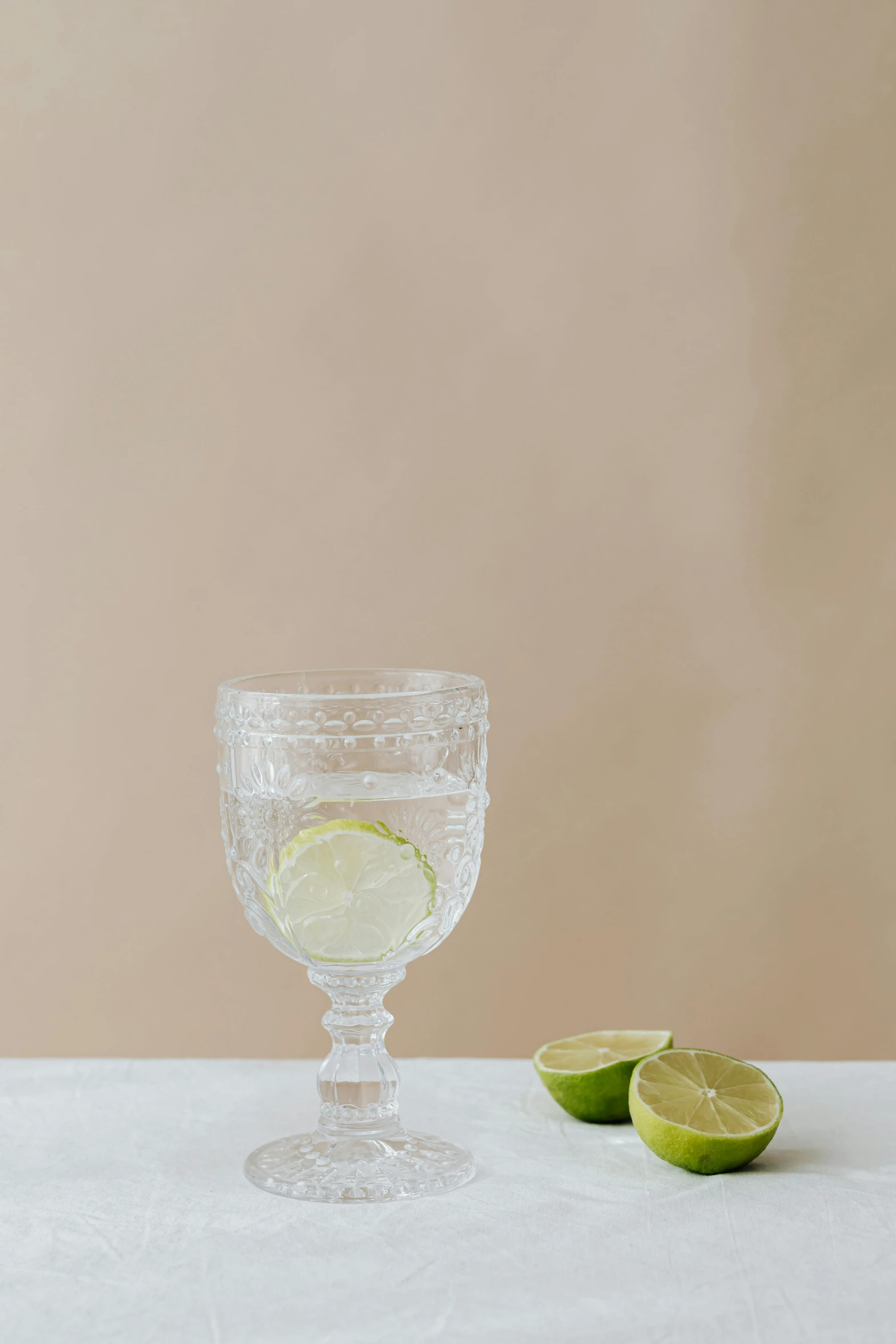 a glass of water with a slice of lime next to it, inspired by Aimé Barraud, renaissance, side view intricate details, glassware, minna sundberg, deckle edge