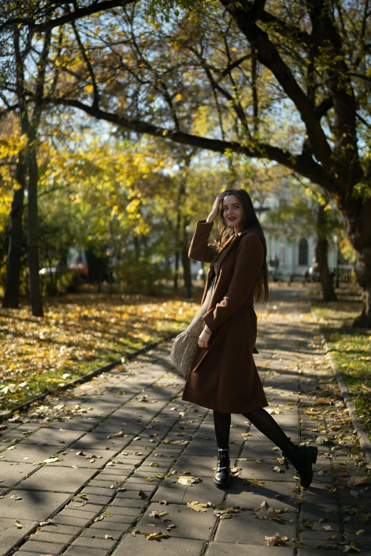 a woman walking down a path in a park, pexels contest winner, long coffee brown hair, in moscow centre, 🍂 cute, satisfied pose