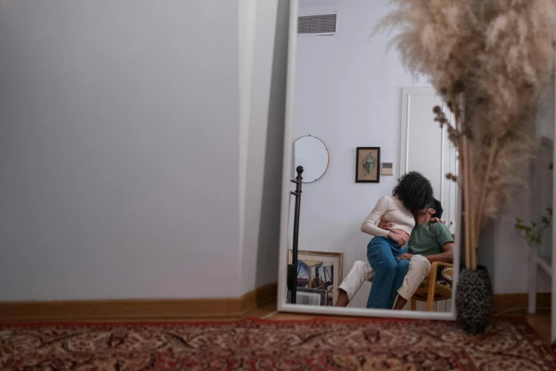 a woman sitting on a chair in front of a mirror, a picture, pexels contest winner, father with child, hugging her knees, anxiety environment, inside a cozy apartment