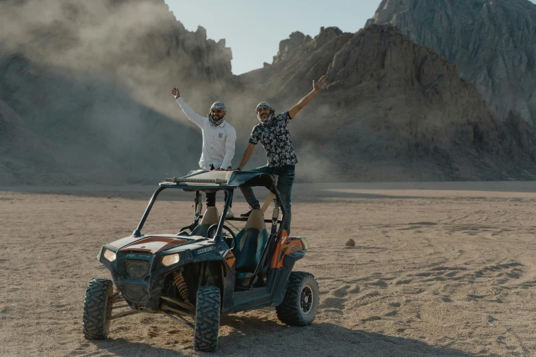 a couple of people riding on the back of a buggy, pexels contest winner, les nabis, dusty rock in background, michael bay style, from egypt, celebrating