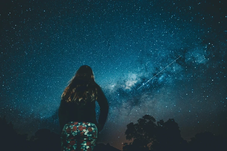 a woman looking up at the night sky, pexels contest winner, ☁🌪🌙👩🏾, space ship in the distance, cosmic girl, star charts