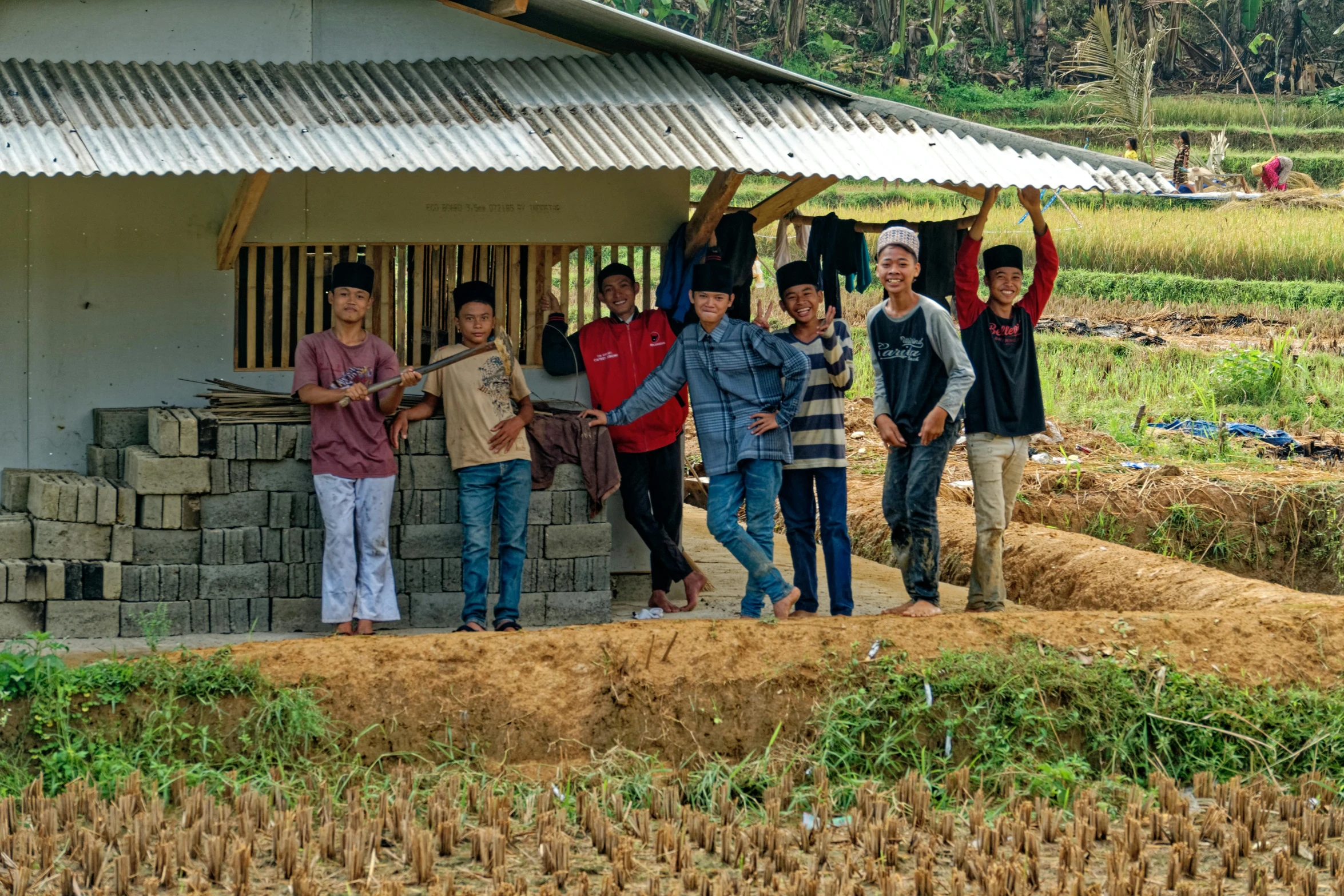 a group of people standing in front of a building, by Kogan Gengei, pexels contest winner, sumatraism, farm land, avatar image, teenage boy, ground-breaking