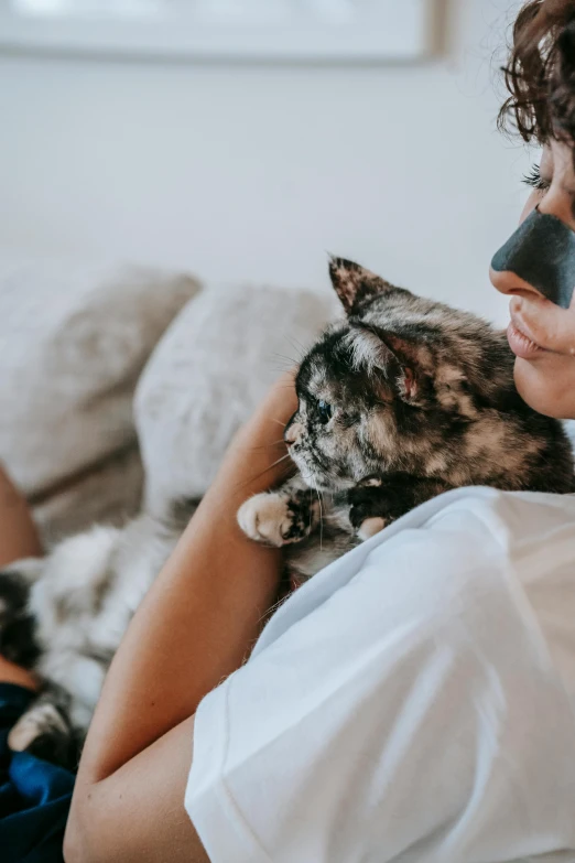 a woman sitting on a couch holding a cat, pexels contest winner, cute bandaid on nose!!, gray mottled skin, masks, profile image