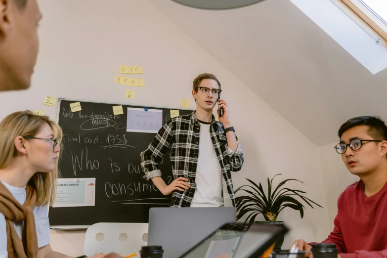 a group of people sitting around a table with laptops, a picture, trending on pexels, arbeitsrat für kunst, a person standing in front of a, whiteboards, cinematic outfit photo, caleb worcester