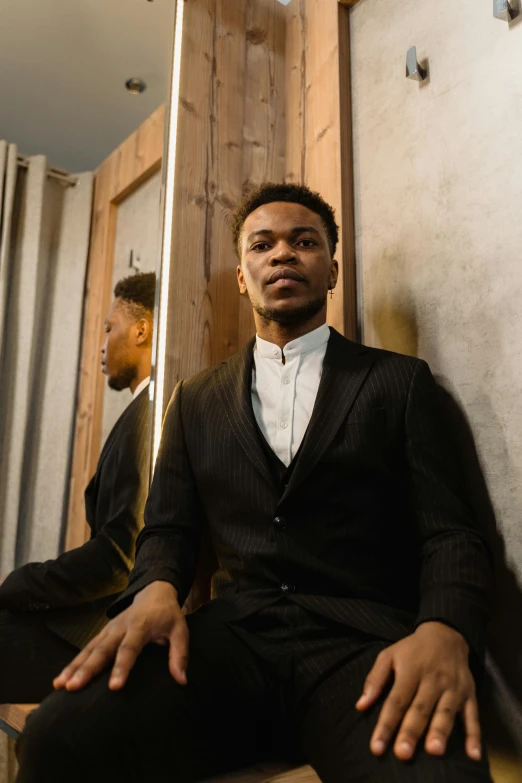 a man in a suit sitting in front of a mirror, an album cover, by Frank Mason, trending on unsplash, renaissance, beautiful young man, ebony rococo, julian ope, subject detail: wearing a suit