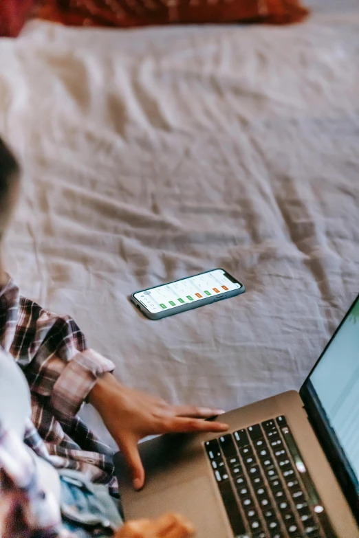 a woman sitting on a bed using a laptop computer, trending on pexels, top down photo, looking at his phone, digital banner, excel running on the computer