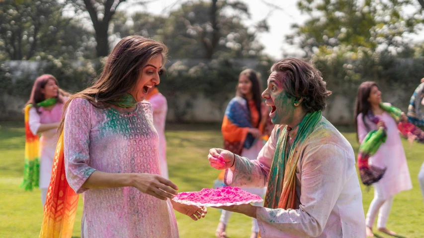 a couple of women standing on top of a lush green field, pexels contest winner, color field, holi festival of rich color, cake, wearing a kurta, actor