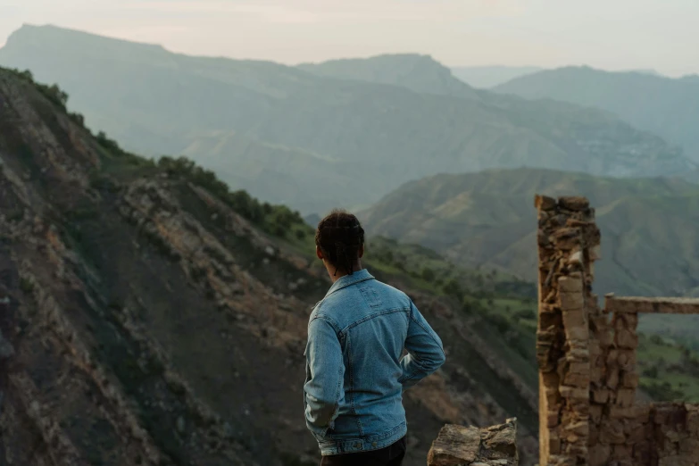 a man standing on top of a mountain overlooking a valley, by Jessie Algie, pexels contest winner, les nabis, standing in ruins, profile image, casually dressed, malibu canyon