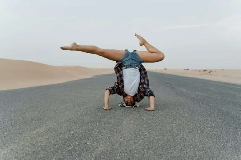 a person doing a handstand in the middle of the road, pexels contest winner, arabesque, arabian wrestling woman, doing a sassy pose, in a desert, casual pose