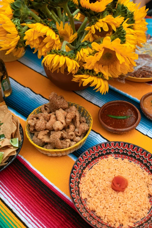 a table topped with plates of food next to a vase of sunflowers, renaissance, mexican desert, square, snacks, product shot