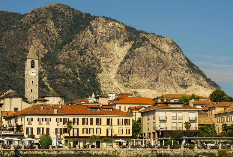 a group of buildings sitting next to a body of water, inspired by Raffeaello Ossola, pexels contest winner, art nouveau, mountain in the background, renzo piano, riverside, geology