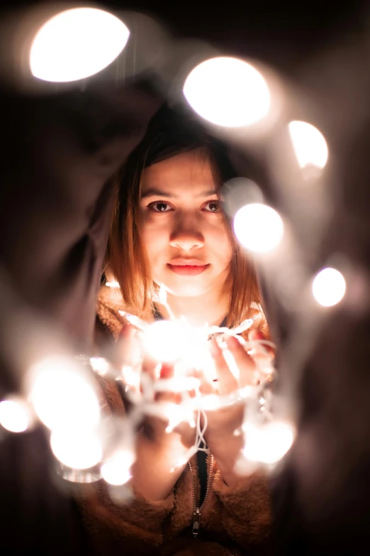 a woman holding a sparkler in front of her face, pexels contest winner, light and space, christmas lights, centered in portrait, a young asian woman, emitting light ornaments