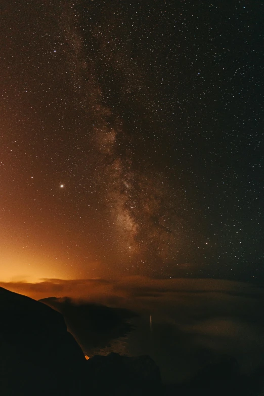 a person standing on top of a mountain under a night sky, pexels contest winner, light and space, dark orange night sky, space ship in the distance, misty space, unsplash 4k