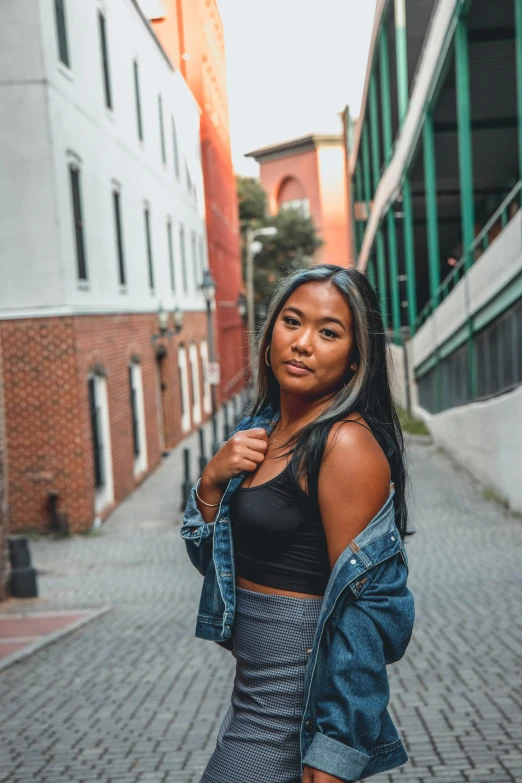 a woman standing in the middle of a street, by Sam Dillemans, trending on unsplash, wearing a cropped black tank top, beautiful young asian woman, leaning against the wall, posing for a picture