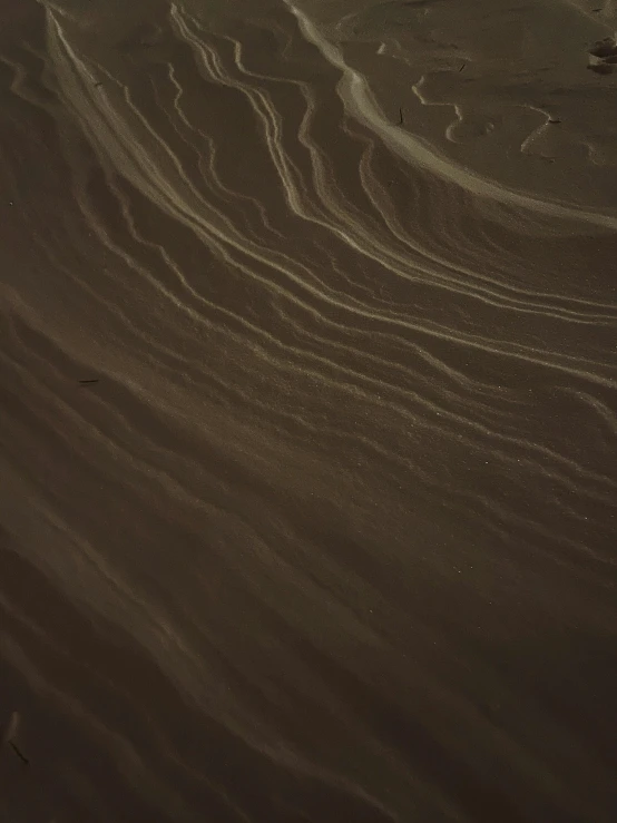 a person riding a snowboard on top of a sandy beach, by Thomas Furlong, pexels contest winner, land art, dark lines, clay texture, low quality video, brown:-2