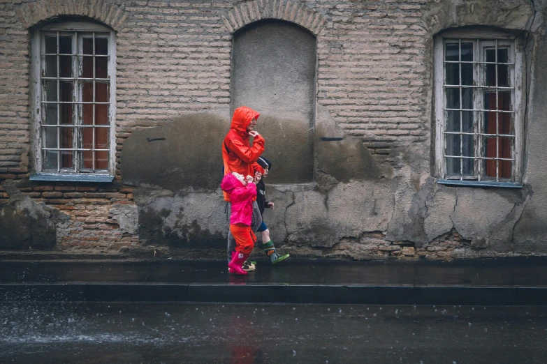 a woman and a child walking in the rain, pexels contest winner, graffiti, orange jacket, unsplash photo contest winner, red clothes, nearest neighbor