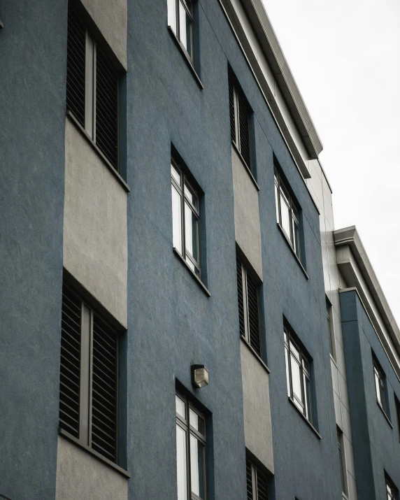 a tall blue building with lots of windows, a black and white photo, unsplash contest winner, stucco walls, ten flats, thumbnail, flat - color