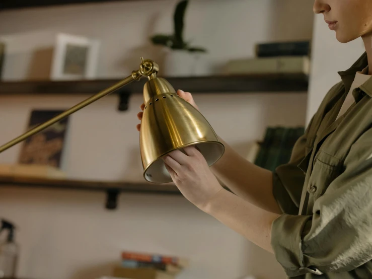 a woman that is holding a lamp in her hand, inspired by Joseph Wright of Derby, pexels contest winner, kinetic art, brass plated, at home, medium close up shot, still from film