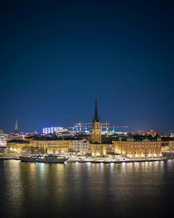 a large body of water next to a city at night, by Tom Wänerstrand, pexels contest winner, swedish style, lgbtq, spires, slightly tanned