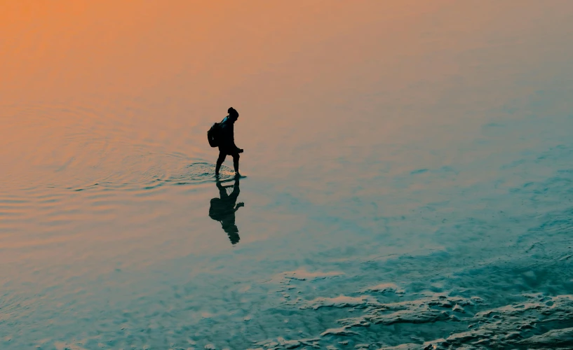 a person standing in the water with a surfboard, pexels contest winner, minimalism, carrying survival gear, in the evening, water reflection on the floor, with a backpack