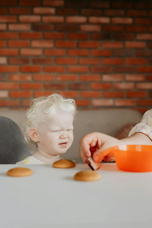 a couple of kids that are sitting at a table, pexels contest winner, cookies, sitting in his highchair, blond, but minimalist